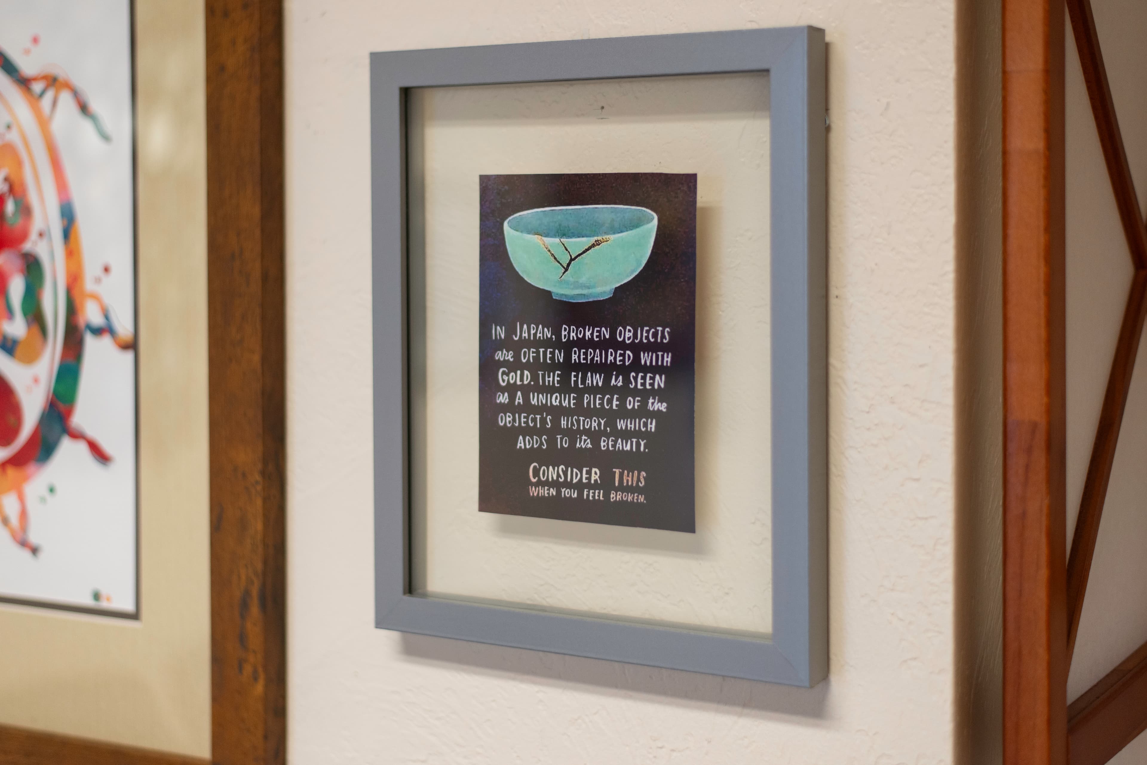 A framed illustration of a kintsugi bowl with the following inscription: "In Japan, broken objects are often repaired with gold. The flaw is seen as a unique piece of the object's history, which adds to its beauty. Consider this when you feel broken."